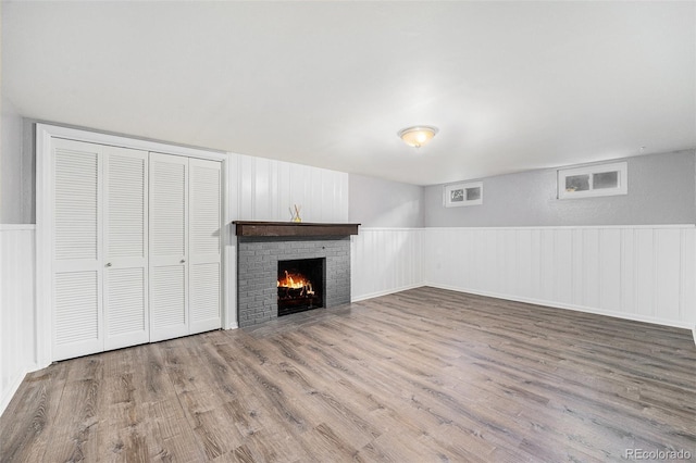 8525 Grandview Ave, Arvada, CO 80002 - unfurnished living room featuring wood finished floors, a fireplace, wainscoting, and a decorative wall