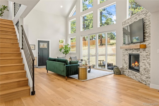 518 Conifer Dr, Bailey, CO 80421 - living room featuring a towering ceiling, light wood-type flooring, stairs, and a stone fireplace