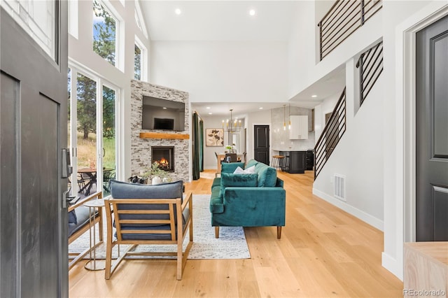 518 Conifer Dr, Bailey, CO 80421 - living area with a high ceiling, a lit fireplace, light wood-style floors, stairs, and a chandelier