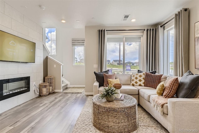 living room with a tiled fireplace and light hardwood / wood-style flooring