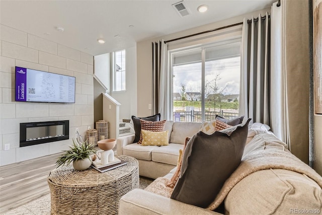 living room featuring light hardwood / wood-style flooring and a tiled fireplace