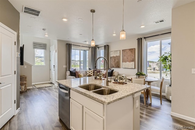 kitchen featuring dishwasher, sink, hanging light fixtures, an island with sink, and white cabinets