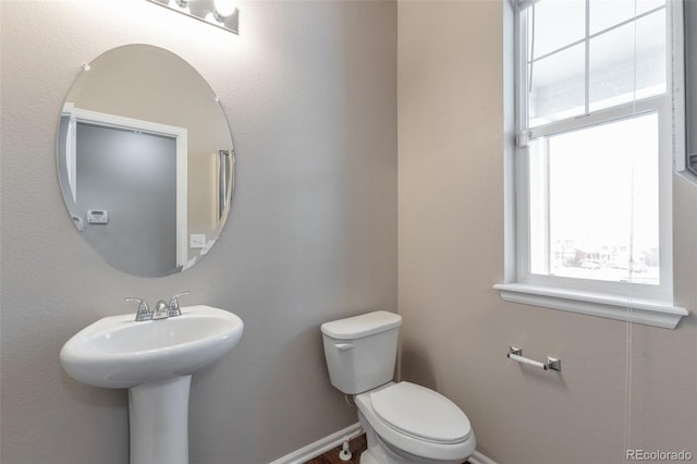 bathroom featuring toilet, baseboards, and a sink