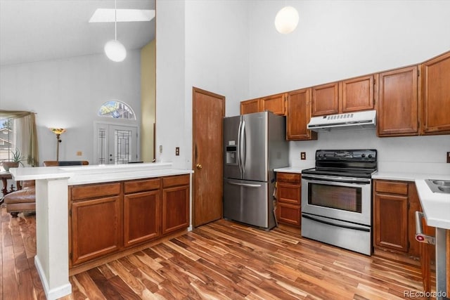 13341 Birch Cir, Thornton, CO 80241 - kitchen featuring stainless steel appliances, under cabinet range hood, a high ceiling, light countertops, and wood finished floors