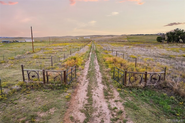 yard at dusk featuring a rural view