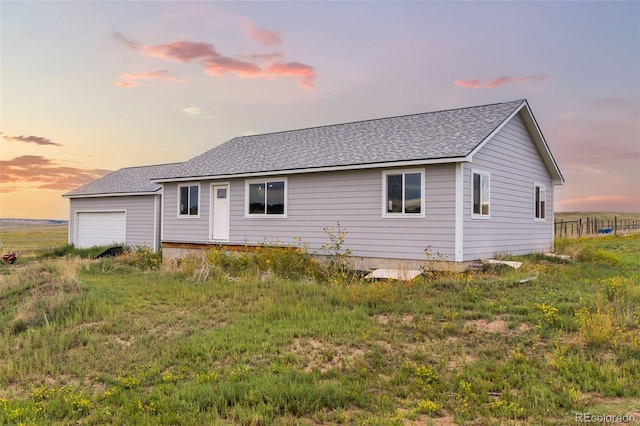 rear view of property with a garage and roof with shingles