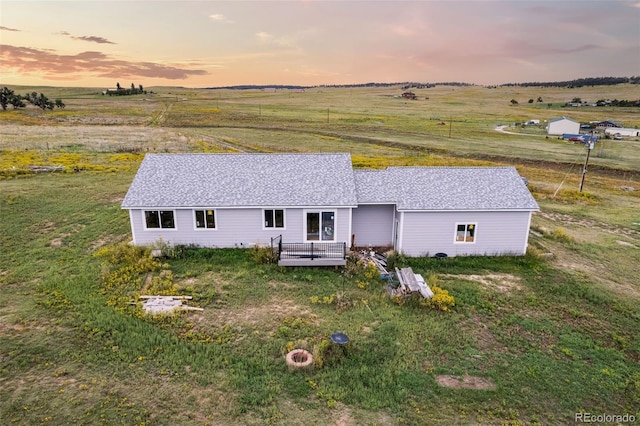 exterior space with a shingled roof, a rural view, and a wooden deck