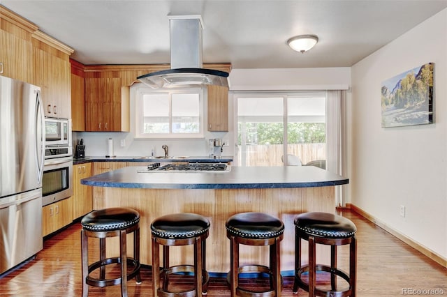 5986 Dunraven St, Golden, CO 80403 - kitchen with appliances with stainless steel finishes, island exhaust hood, a breakfast bar, dark countertops, and a kitchen island