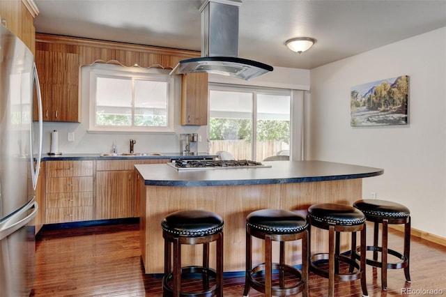 5986 Dunraven St, Golden, CO 80403 - kitchen featuring island range hood, a sink, stainless steel appliances, a kitchen bar, and dark countertops