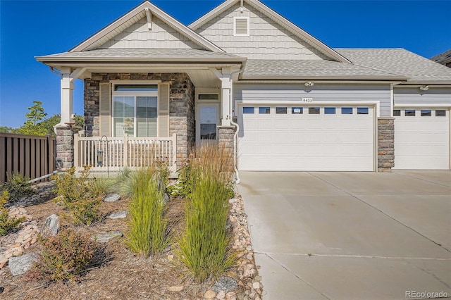 4403 Picadilly Ct, Aurora, CO 80019 - craftsman-style house featuring stone siding, a garage, driveway, roof with shingles, and a porch
