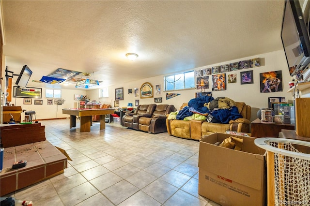 game room with a textured ceiling, light tile patterned flooring, and billiards