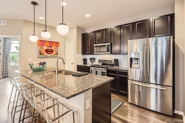 1519 S Dayton St, Denver, CO 80247 - kitchen with stainless steel appliances, light stone countertops, wood finished floors, a breakfast bar area, and recessed lighting