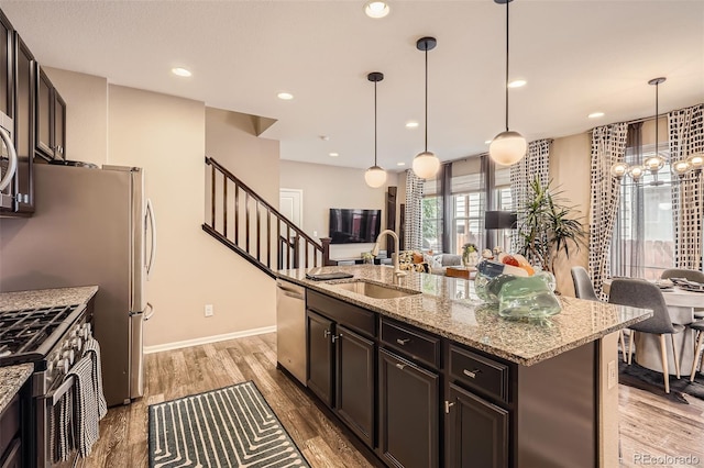 1519 S Dayton St, Denver, CO 80247 - kitchen with stainless steel appliances, light stone countertops, light wood-style floors, open floor plan, and recessed lighting