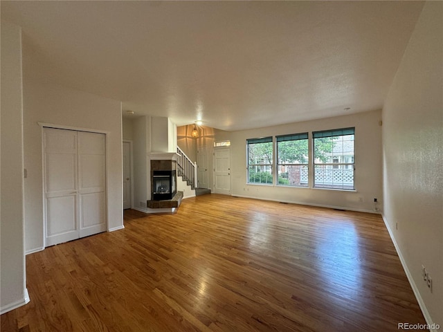 unfurnished living room featuring a tile fireplace and light hardwood / wood-style floors