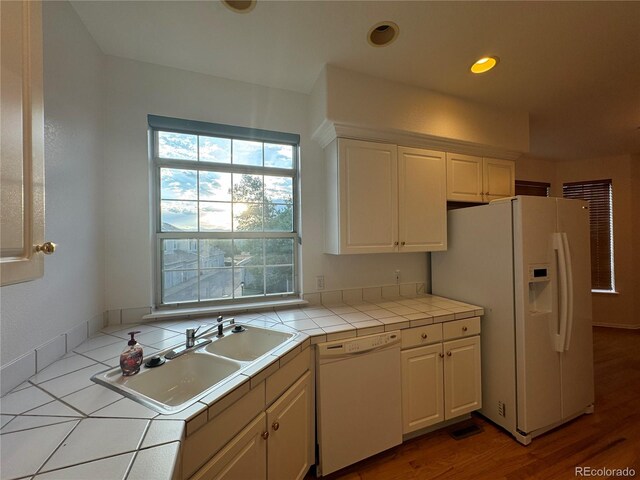 kitchen with white cabinets, sink, white appliances, wood-type flooring, and tile counters