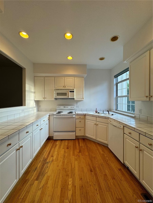 kitchen featuring white cabinets, sink, light hardwood / wood-style floors, and white appliances