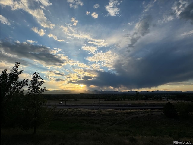 yard at dusk featuring a mountain view and a rural view