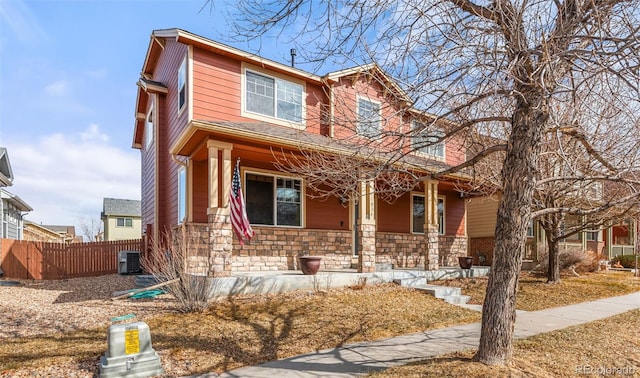 view of front of home featuring a porch, stone siding, central AC, and fence