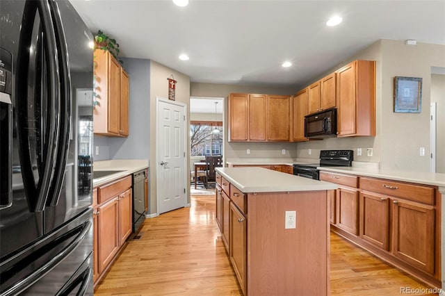 kitchen with light wood-style floors, a center island, light countertops, and black appliances