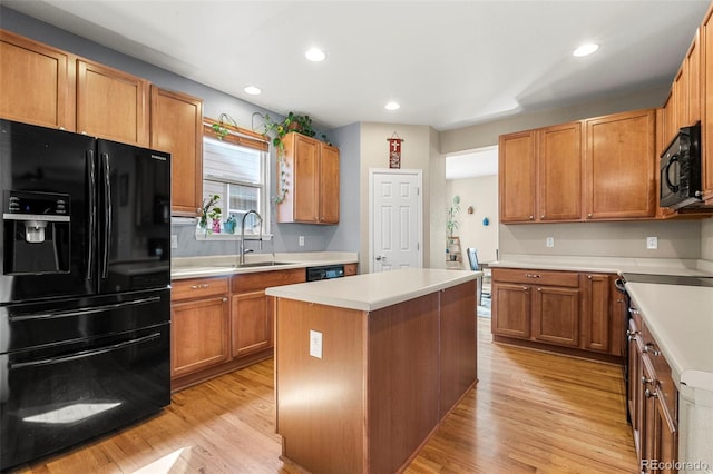 kitchen featuring a sink, light wood-style floors, light countertops, a center island, and black appliances