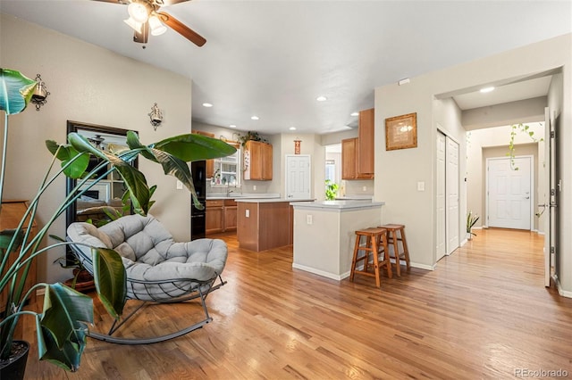 interior space with recessed lighting, a peninsula, open floor plan, light wood-type flooring, and brown cabinets
