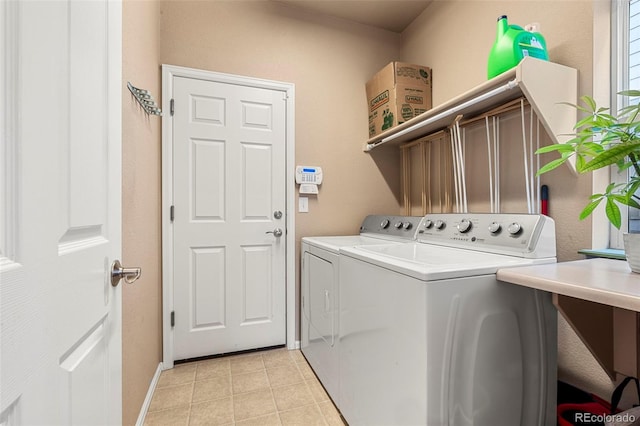 washroom featuring light tile patterned flooring, washing machine and clothes dryer, cabinet space, and baseboards