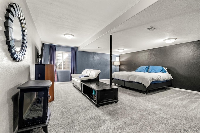 bedroom with a textured ceiling, a textured wall, visible vents, baseboards, and carpet