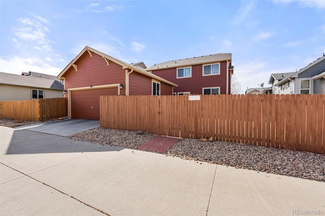 view of side of home with concrete driveway, fence, and an attached garage