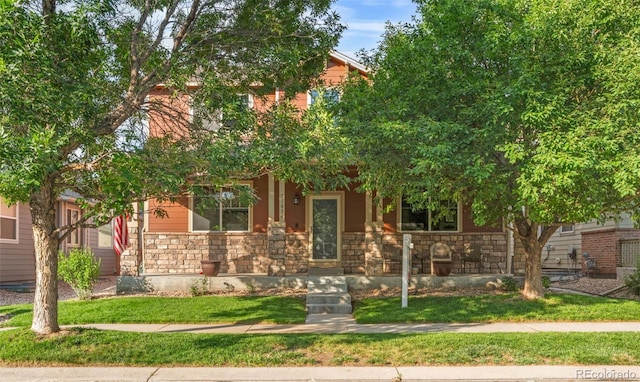11034 Nome St, Commerce City, CO 80640 - view of property hidden behind natural elements with stone siding, a front lawn, and a porch