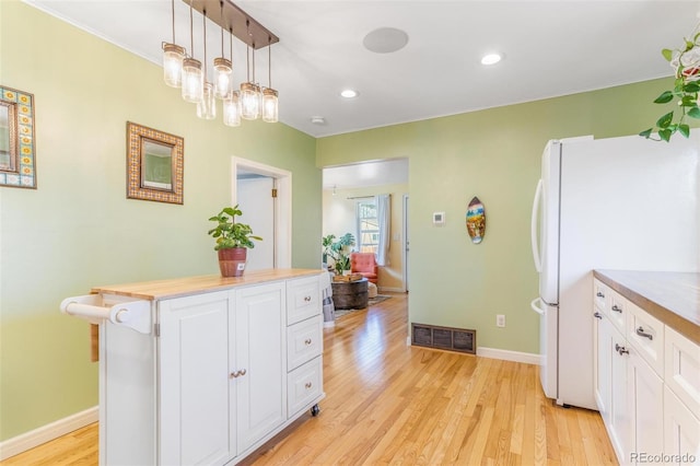4476 S Lincoln St, Englewood, CO 80113 - kitchen with light wood finished floors, white cabinetry, visible vents, and freestanding refrigerator