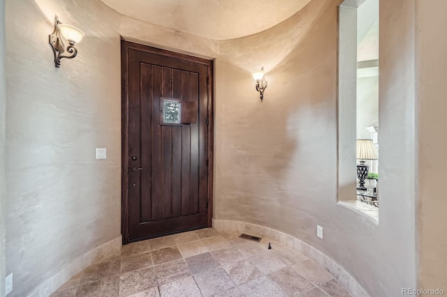 interior space with stone tile floors, baseboards, and visible vents