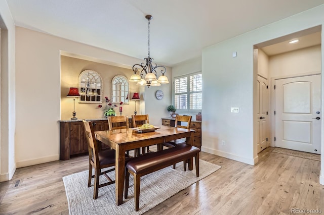 dining room featuring baseboards, a notable chandelier, and light wood-style flooring