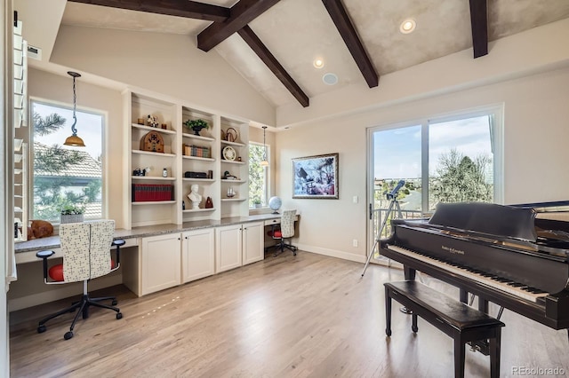 office with built in study area, light wood-style floors, lofted ceiling with beams, and a healthy amount of sunlight