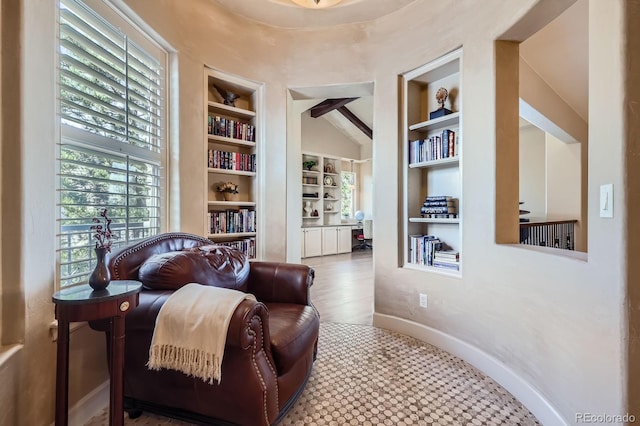 living area with baseboards, lofted ceiling, built in shelves, and wood finished floors