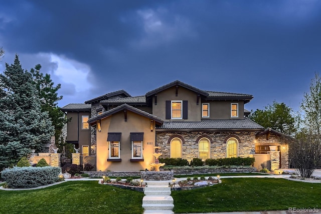 view of front of house with a tile roof, a front lawn, stone siding, and stucco siding