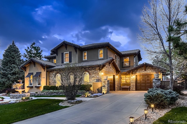 view of front of house with a tile roof, stone siding, stucco siding, a front yard, and concrete driveway