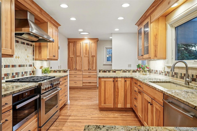 10849 E Crestridge Cir, Englewood, CO 80111 - kitchen featuring appliances with stainless steel finishes, wall chimney range hood, a sink, light wood-style flooring, and recessed lighting