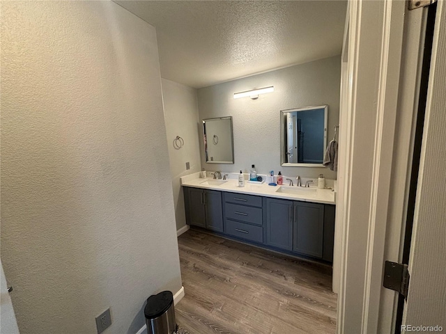 bathroom featuring vanity, wood-type flooring, and a textured ceiling