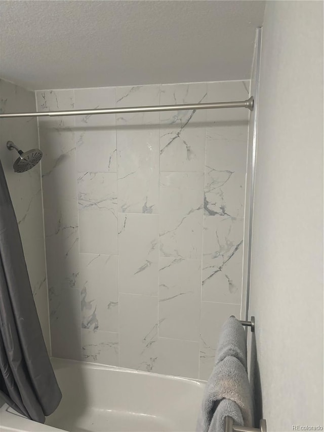 bathroom featuring a textured ceiling and shower / bathtub combination with curtain