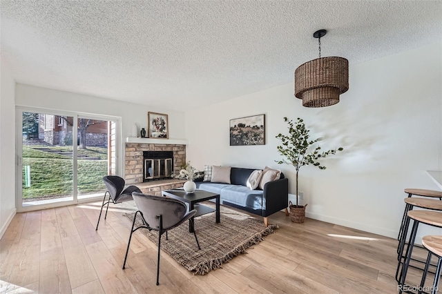 living room with light wood-type flooring, a fireplace, and a textured ceiling