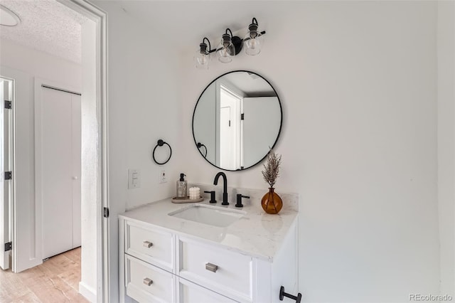 bathroom with a textured ceiling, vanity, and wood finished floors