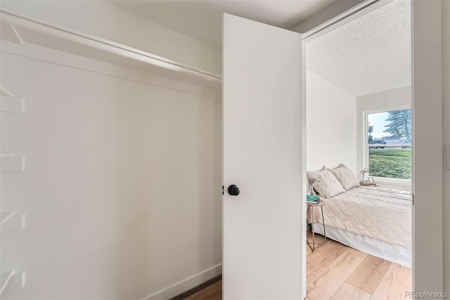 bedroom featuring light wood-style flooring, baseboards, and a textured ceiling