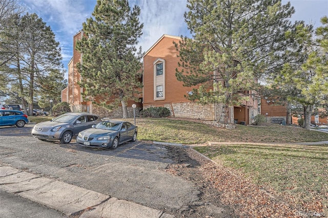 view of front of house with uncovered parking and a front lawn