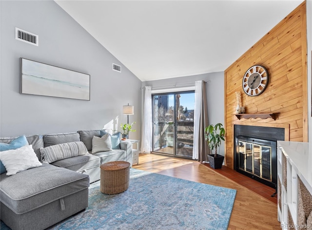 living room featuring vaulted ceiling, hardwood / wood-style floors, and wood walls