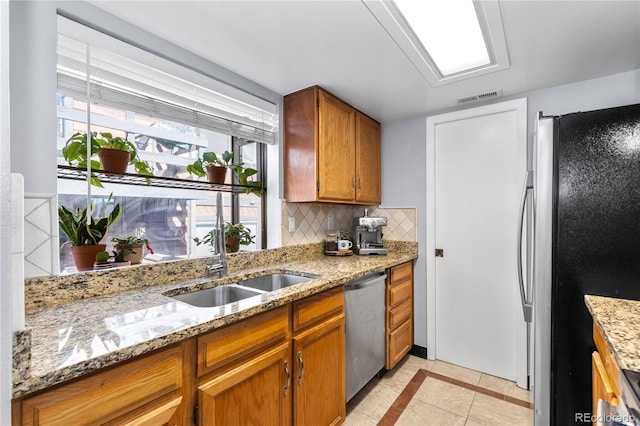 kitchen featuring sink, light tile patterned floors, stainless steel appliances, light stone counters, and decorative backsplash