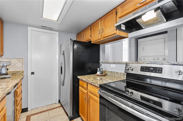 kitchen with light stone counters, light tile patterned floors, tasteful backsplash, and appliances with stainless steel finishes