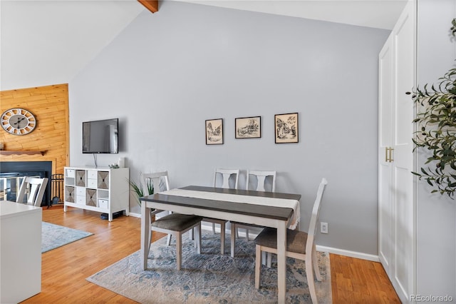 dining space with beamed ceiling, hardwood / wood-style flooring, and high vaulted ceiling