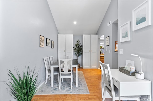 dining space with vaulted ceiling and light hardwood / wood-style floors