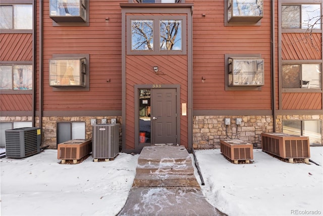 snow covered property entrance featuring central air condition unit