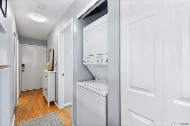 laundry room featuring stacked washer and dryer and light hardwood / wood-style floors